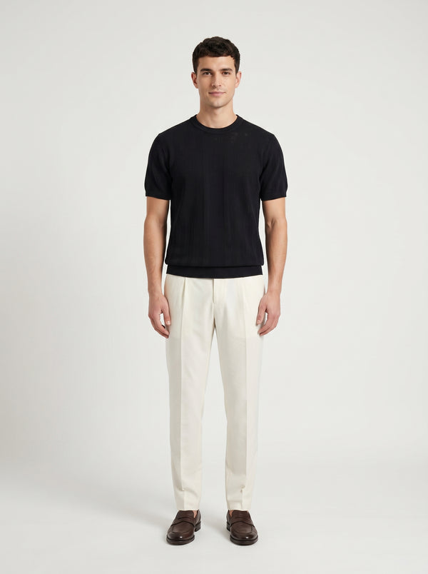 Man wearing a black t-shirt and white pants on a light gray background